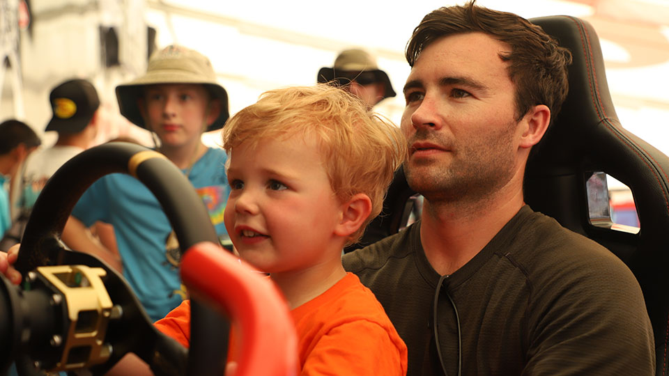 A father and child use a racing simulator